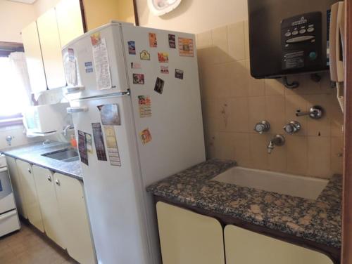 cocina con heladera blanca y fregadero en Edificio Mirasoles en Villa Gesell