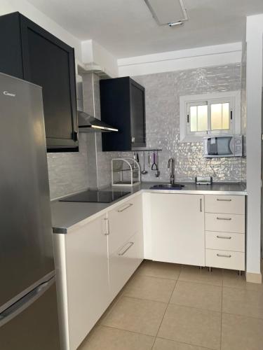 a kitchen with white cabinets and a stainless steel refrigerator at APARTAMENTO EN LOS CRISTIANOS - FREE WIFI in Los Cristianos