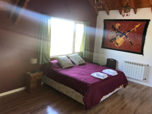 a bedroom with a bed with purple sheets and a window at LA CASONA in Villa General Belgrano