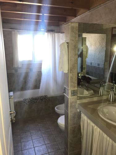 a bathroom with two sinks and a toilet and a window at LA CASONA in Villa General Belgrano