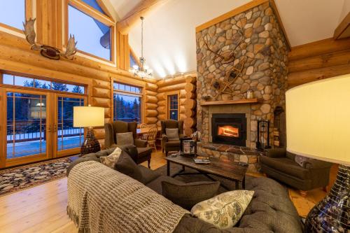 a living room with a stone fireplace in a log house at Moberly Lodge in Golden