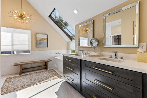 a bathroom with a sink and a mirror and a tub at La Paloma in Dana Point