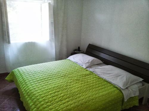 a bedroom with a green bed with a window at Apartments by the sea Brna, Korcula - 17583 in Smokvica