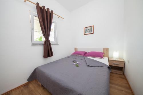 ein Schlafzimmer mit einem Bett mit lila Kissen und einem Fenster in der Unterkunft Apartments with a parking space Pridraga - Cuskijas, Novigrad - 17619 in Pridraga