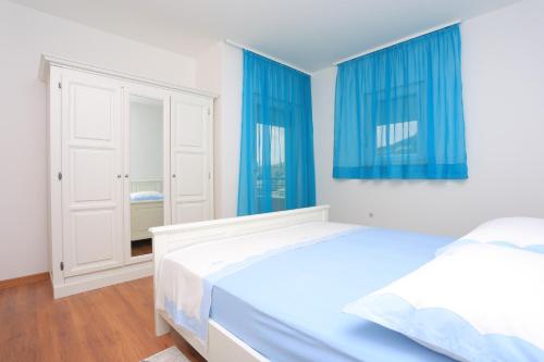 1 Schlafzimmer mit 2 Betten und blauen Vorhängen in der Unterkunft Apartment Solin 17669a in Solin