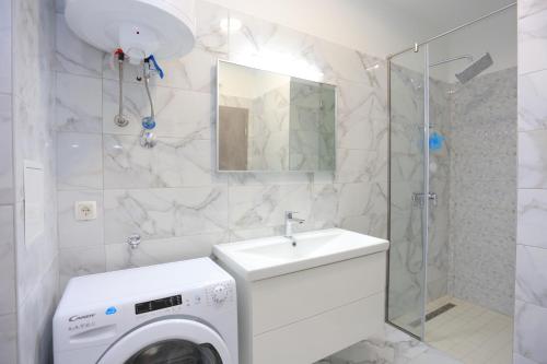 ein Badezimmer mit einer Waschmaschine und einem Waschbecken in der Unterkunft Apartment Solin 17669a in Solin