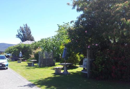 a park with benches and a fence and a tree at Edgewater Motel in Te Anau