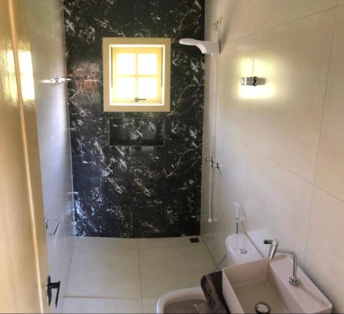 baño con ducha, lavabo y ventana en Casa Ouro no centro de Diamantina en Diamantina