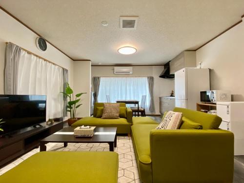 a living room with two green chairs and a television at ワンハウス新小岩 in Tokyo