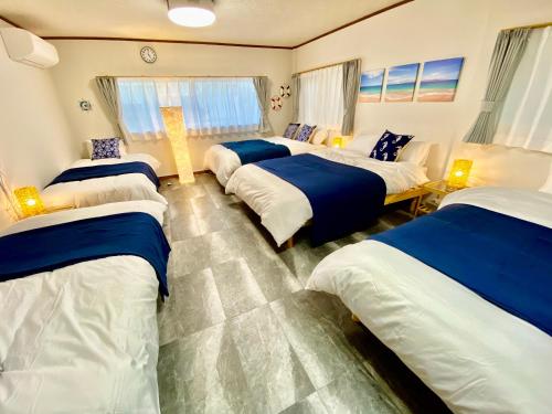 a room with four beds with blue and white sheets at ワンハウス新小岩 in Tokyo
