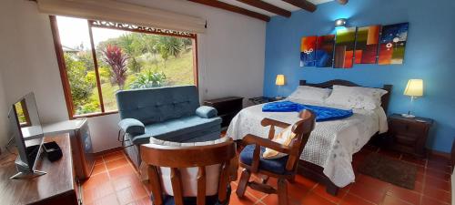 a bedroom with a bed and a chair and a window at Casa Hotel San Pedro in Villa de Leyva