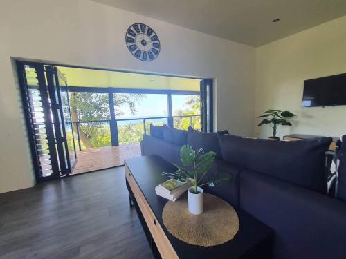 a living room with a blue couch and a clock at Tematas Mountain Villa in Avarua