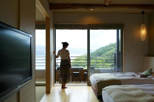 a woman standing in a hotel room looking out the window at Uminohana in Atami