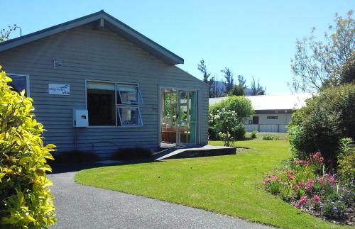 a house with a window and a grass yard at Edgewater Motel in Te Anau