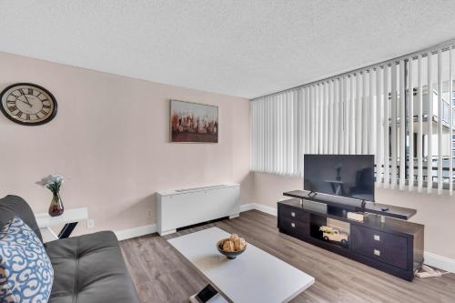 Arlington 2BR 2Ba Apartment in Crystal City apts في أرلينغتون: غرفة معيشة مع أريكة وساعة على الحائط