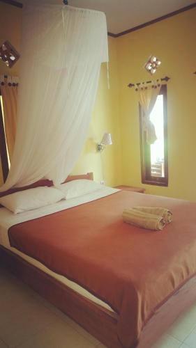 a bedroom with a large bed with a curtain on it at Family bungalow in Gili Meno