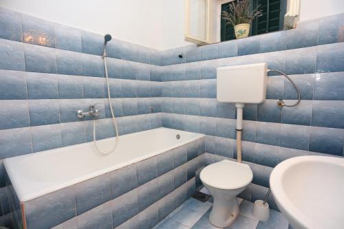 La salle de bains est pourvue de carrelage bleu, de toilettes et d'une baignoire. dans l'établissement Apartments by the sea Sumpetar, Omis - 17810, à Jesenice
