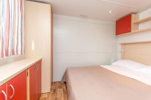 ein kleines Schlafzimmer mit einem Bett und roten Schränken in der Unterkunft Family friendly apartments with a swimming pool Drage, Biograd - 17819 in Pakoštane