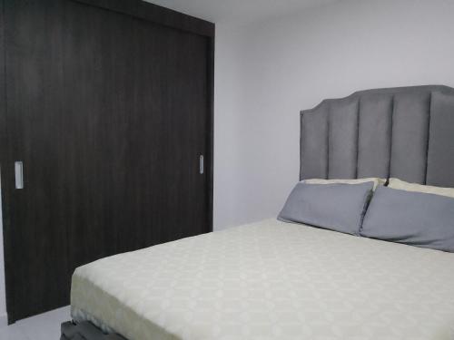 een slaapkamer met een groot bed met een grijs hoofdeinde bij Apartamento en el centro de la ciudad bonita a muy buen precio in Bucaramanga