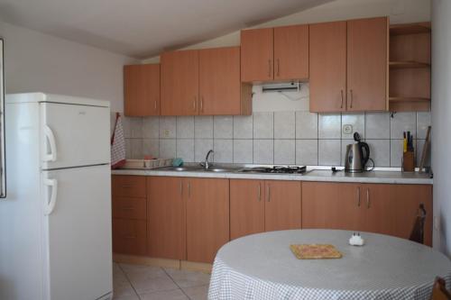 kuchnia ze stołem i białą lodówką w obiekcie Apartments by the sea Starigrad, Paklenica - 17865 w mieście Starigrad-Paklenica