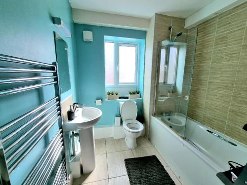 een blauwe badkamer met een toilet en een wastafel bij Luxury 2-Bedroom Service Apartment with Balcony in Manchester