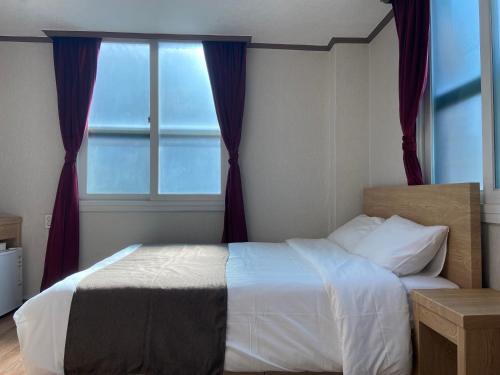 a bedroom with a bed with a large window at Bricks Stay Jeju City & Aiport in Jeju