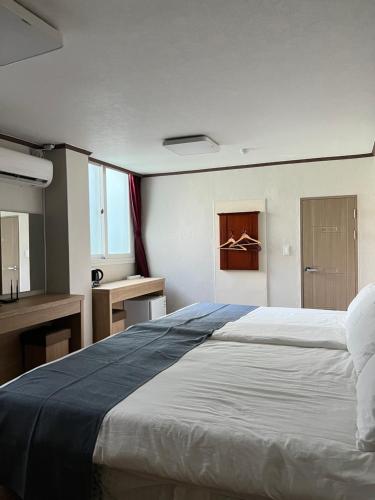 um quarto com uma cama grande e uma secretária em Bricks Stay Jeju City & Aiport em Jeju