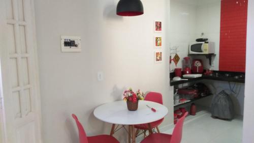 a kitchen with a white table and red chairs at Flor de Peroba Flats #3 Vermelho - Maragogi - AL in Maragogi