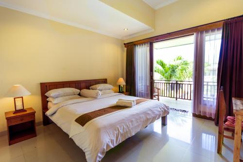 a bedroom with a large bed and a balcony at Sakura Guest House in Canggu