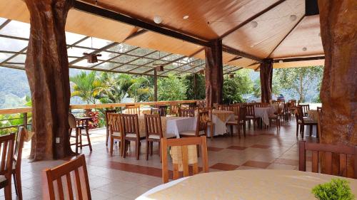 un restaurante vacío con mesas, sillas y árboles en Hostería Castillo Real en Zamora