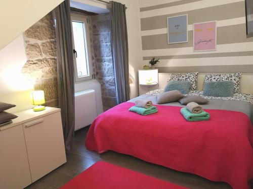 sypialnia z czerwonym łóżkiem i 2 ręcznikami w obiekcie Apartments and rooms with parking space Hum, Central Istria - Sredisnja Istra - 17939 w mieście Roč