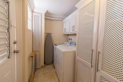 baño pequeño con lavabo y lavadora en Bianca Bay 3 Bedroom West Coast Beach Front Villa en Saint James