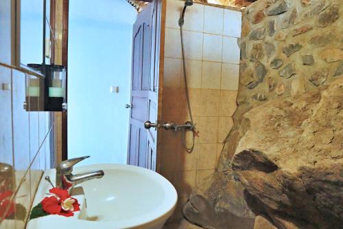 baño con lavabo y pared de piedra en Selang Resort, en Amed