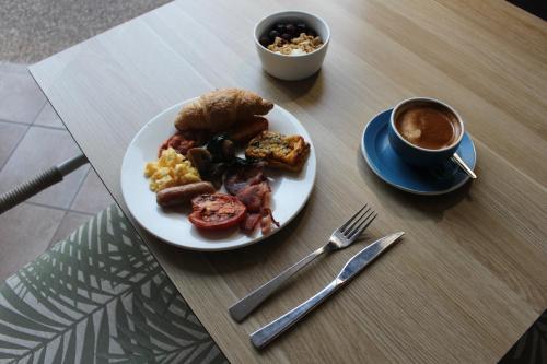 uma mesa com um prato de comida para o pequeno-almoço e uma chávena de café em Coral Cay Resort em Mackay