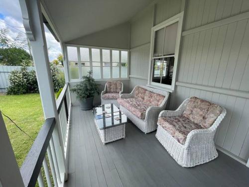 two wicker chairs and a table on a porch at Finney Cottage in Stanthorpe