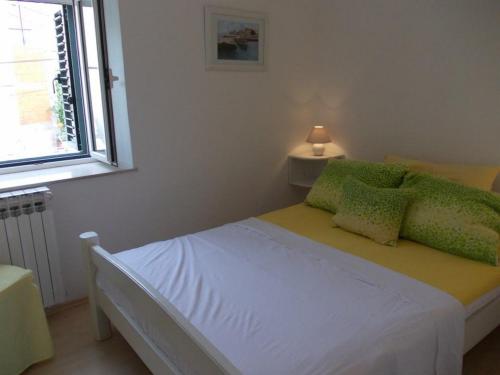 - une chambre avec un lit doté d'oreillers verts et d'une fenêtre dans l'établissement Apartments by the sea Primosten - 17975, à Primošten