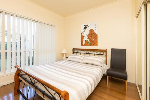 a bedroom with a large bed and a chair at Seachange in Forster