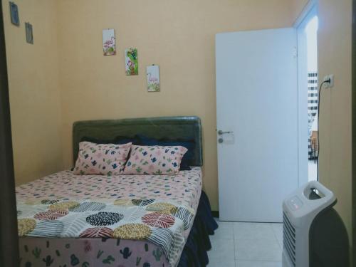 ein Schlafzimmer mit einem Bett mit einer Bettdecke und Kissen in der Unterkunft The Garden Homestay Syariah dekat Batu, pintu tol, UB, UMM in Blimbing