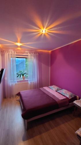 - une chambre avec un lit aux murs violets et une fenêtre dans l'établissement Widokowa Apartament, à Szczecin