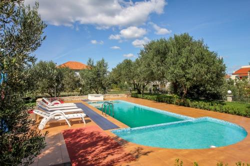 een zwembad met 2 stoelen en een tafel bij Family friendly apartments with a swimming pool Nevidjane, Pasman - 18054 in Neviđane