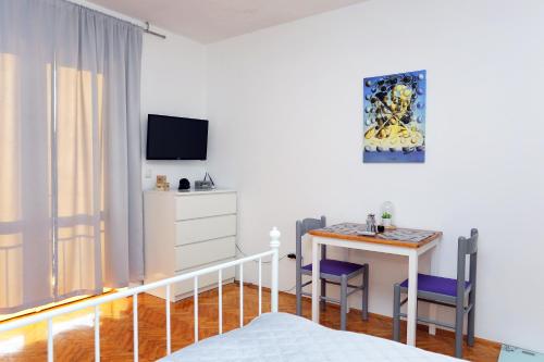 a bedroom with a bed and a table and a tv at Apartments and rooms with parking space Makarska - 18028 in Makarska