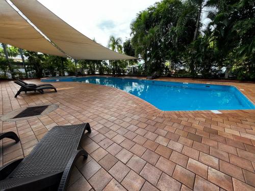 uma piscina com dois bancos e um guarda-sol em Darwin Esplanade Central Official em Darwin