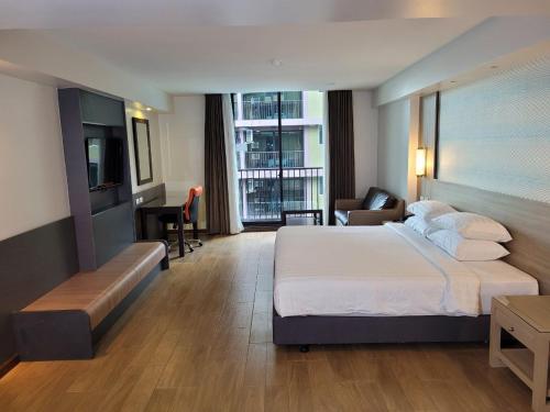 een hotelkamer met een groot bed en een bureau bij Dynasty Grande Hotel in Bangkok