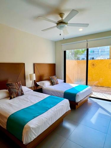a bedroom with two beds and a ceiling fan at Lujoso departamento en el corazón de Playa in Playa del Carmen