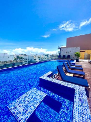 a swimming pool with lounge chairs on top of a building at Lujoso departamento en el corazón de Playa in Playa del Carmen