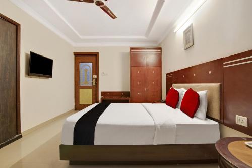a bedroom with a large bed with red pillows at Capital O Elegant Amethyst Business Hotel Near Ragigudda Sri Prasanna Anjaneyaswamy Temple in Bengaluru