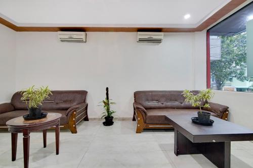 a living room with leather couches and potted plants at Capital O Elegant Amethyst Business Hotel Near Ragigudda Sri Prasanna Anjaneyaswamy Temple in Bengaluru