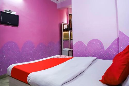1 dormitorio con 1 cama con pared de color rosa en OYO 45569 Goyal's Inn, en Ajmer