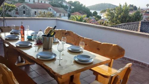 einen Holztisch mit Tellern und Weingläsern auf einer Terrasse in der Unterkunft Apartments by the sea Razanj, Rogoznica - 18089 in Rogoznica