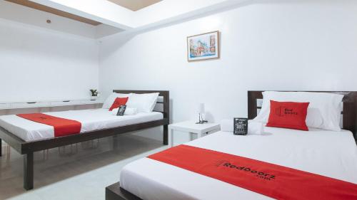 two beds in a room with red and white at RedDoorz near UST Sampaloc Manila in Manila